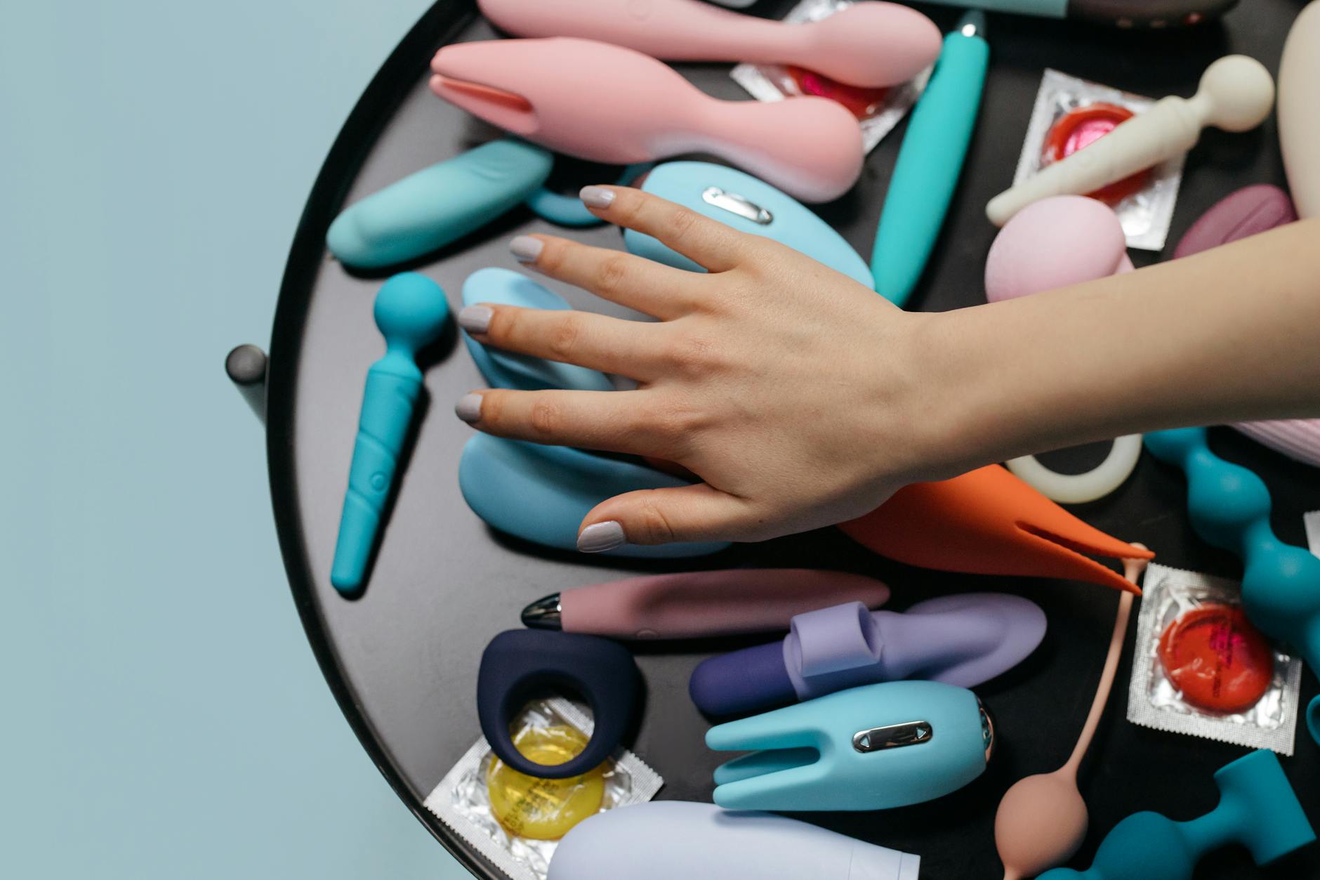 A vibrant silicone vibrator held in hand against a purple background, representing self-care and modern pleasure tools