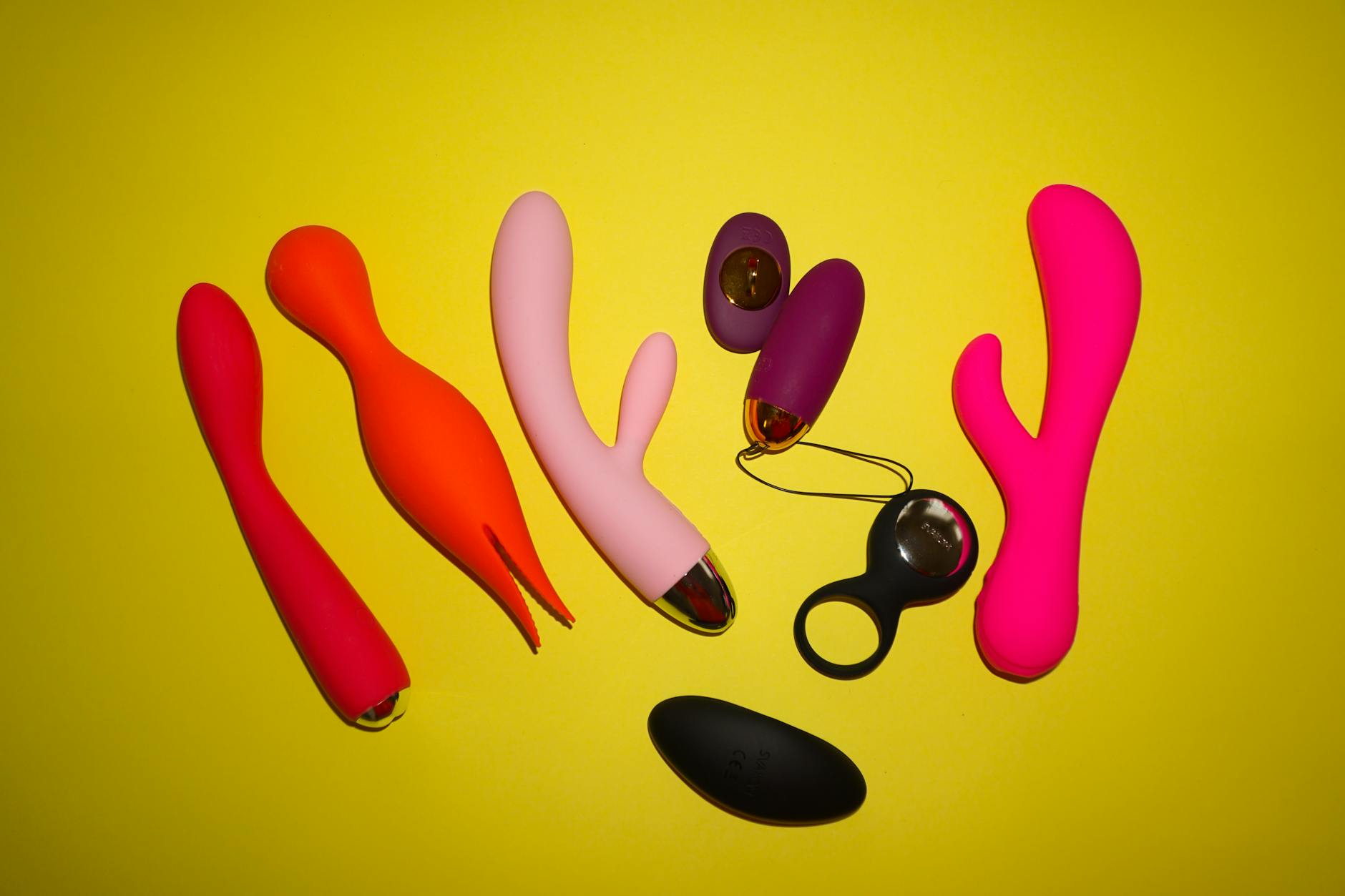 Woman holding colorful vibrators with a contemplative expression